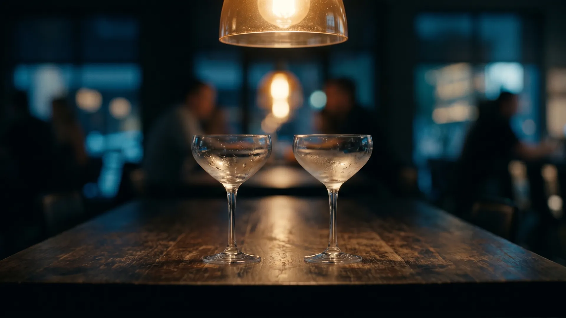 Two cocktail glasses on a dimly lit bar table
